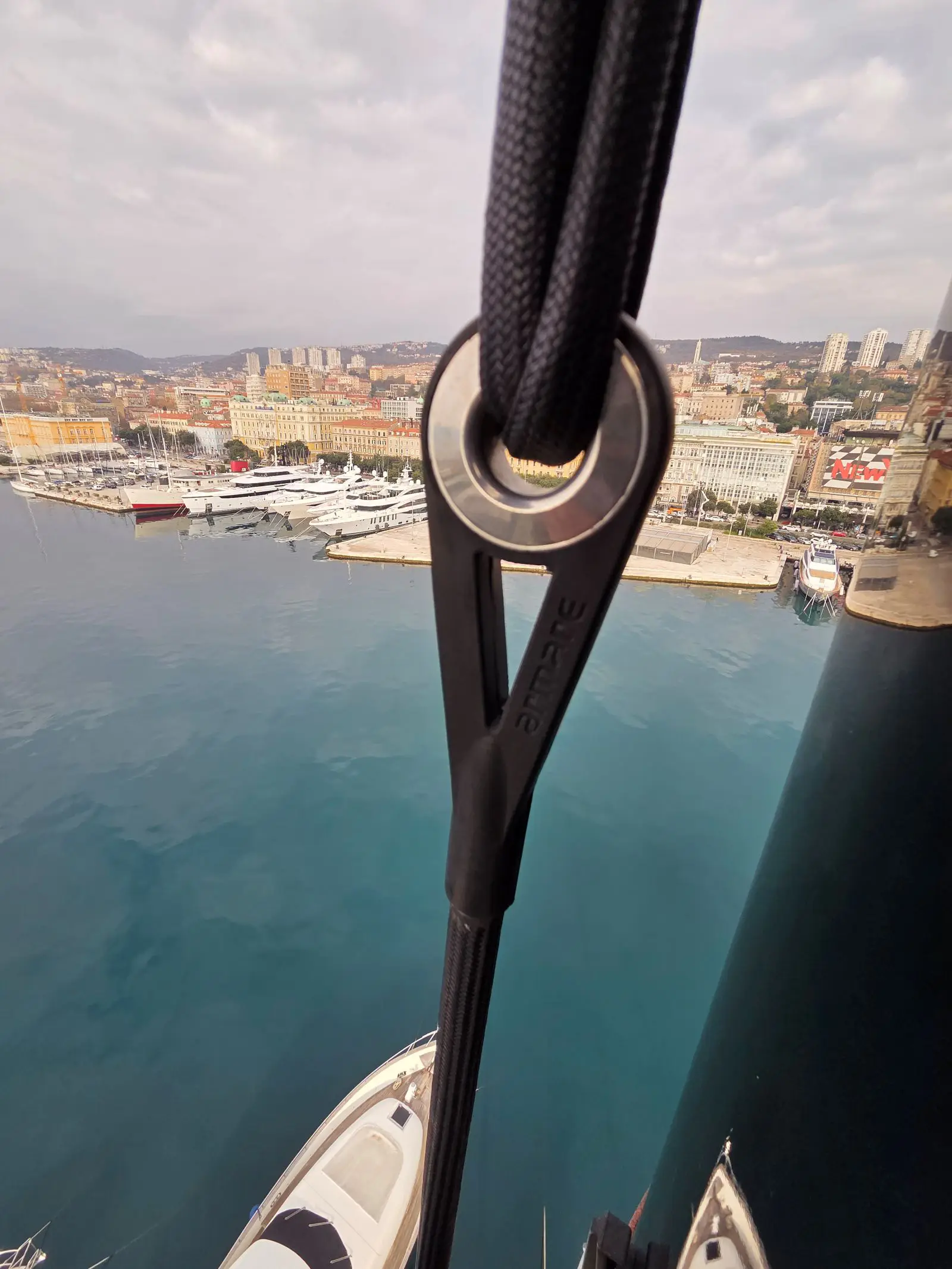 Detalj konopa jedrilice provučenog kroz palubnu opremu s marinom i morem u pozadini