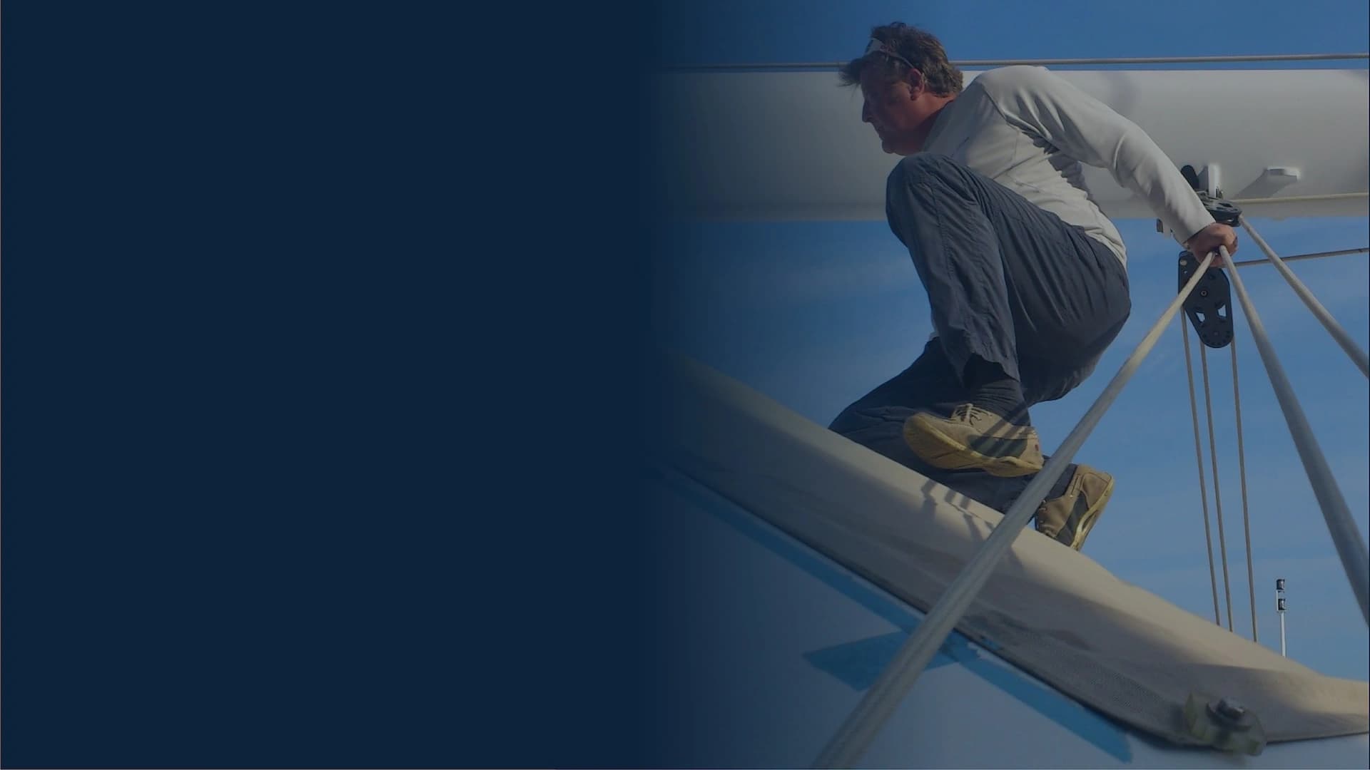 Rigging specialist working high on a sailboat mast, showing hands-on expertise in mast and rigging systems