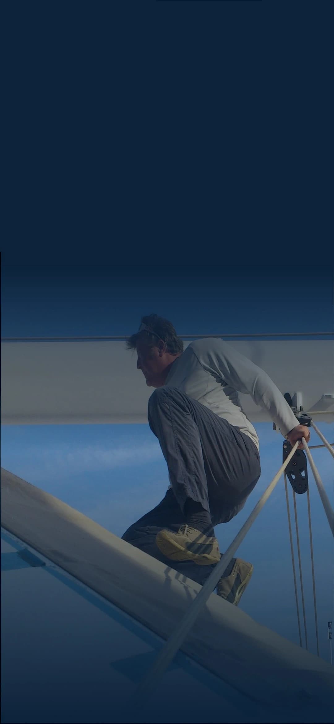 Rigging specialist working high on a sailboat mast, showing hands-on expertise in mast and rigging systems