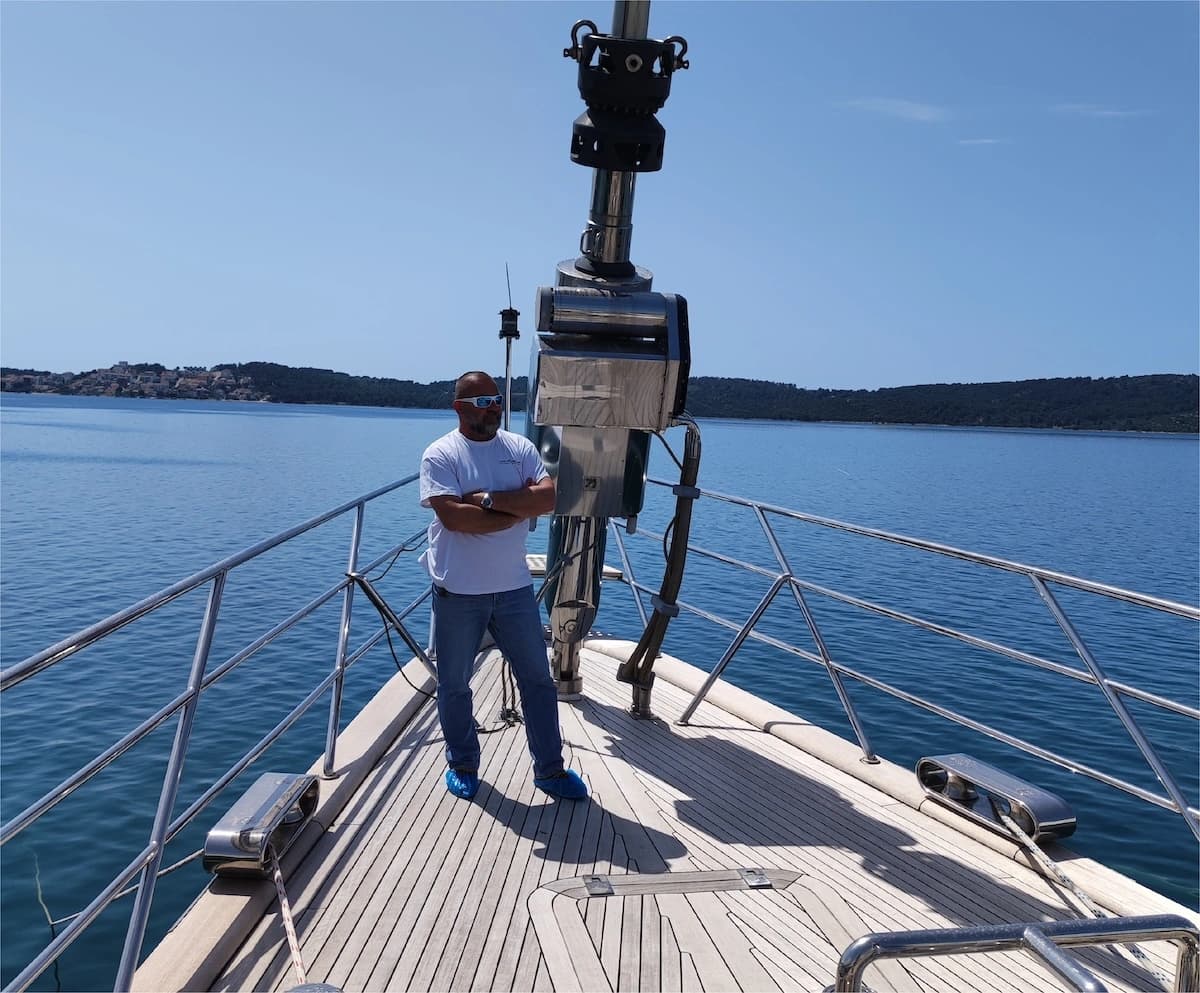 Person standing on the bow of a sailing yacht during rigging inspection or service at sea