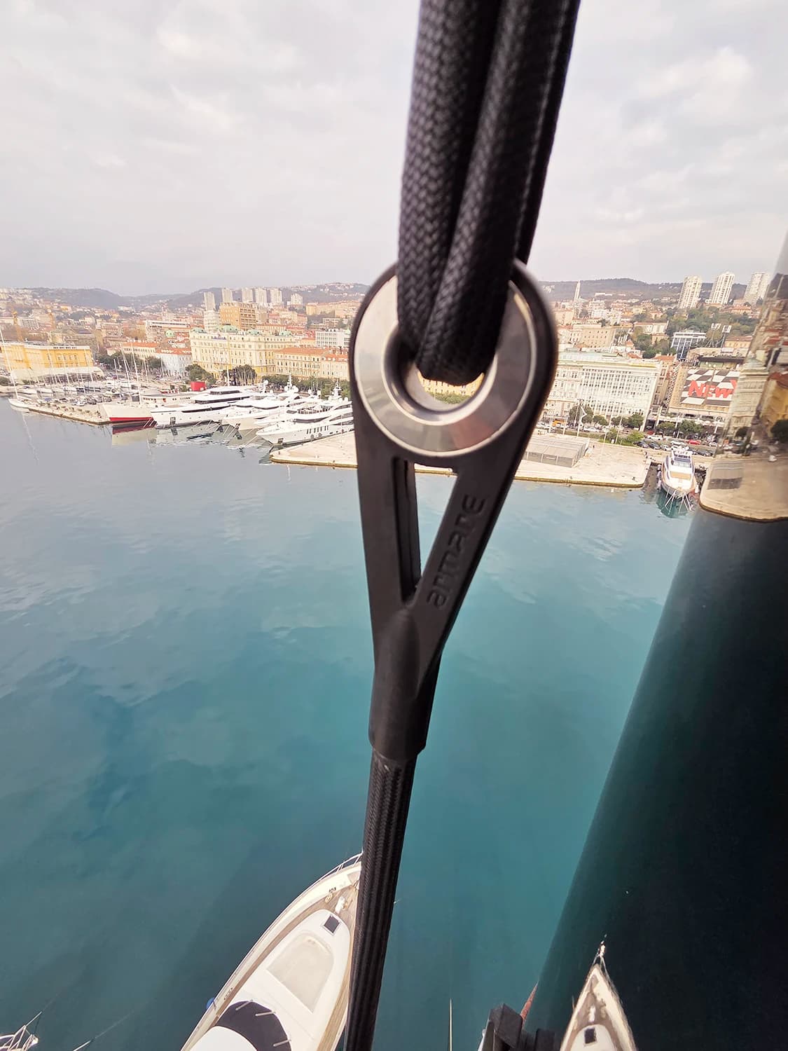 Detalj konopa jedrilice provučenog kroz palubnu opremu s marinom i morem u pozadini