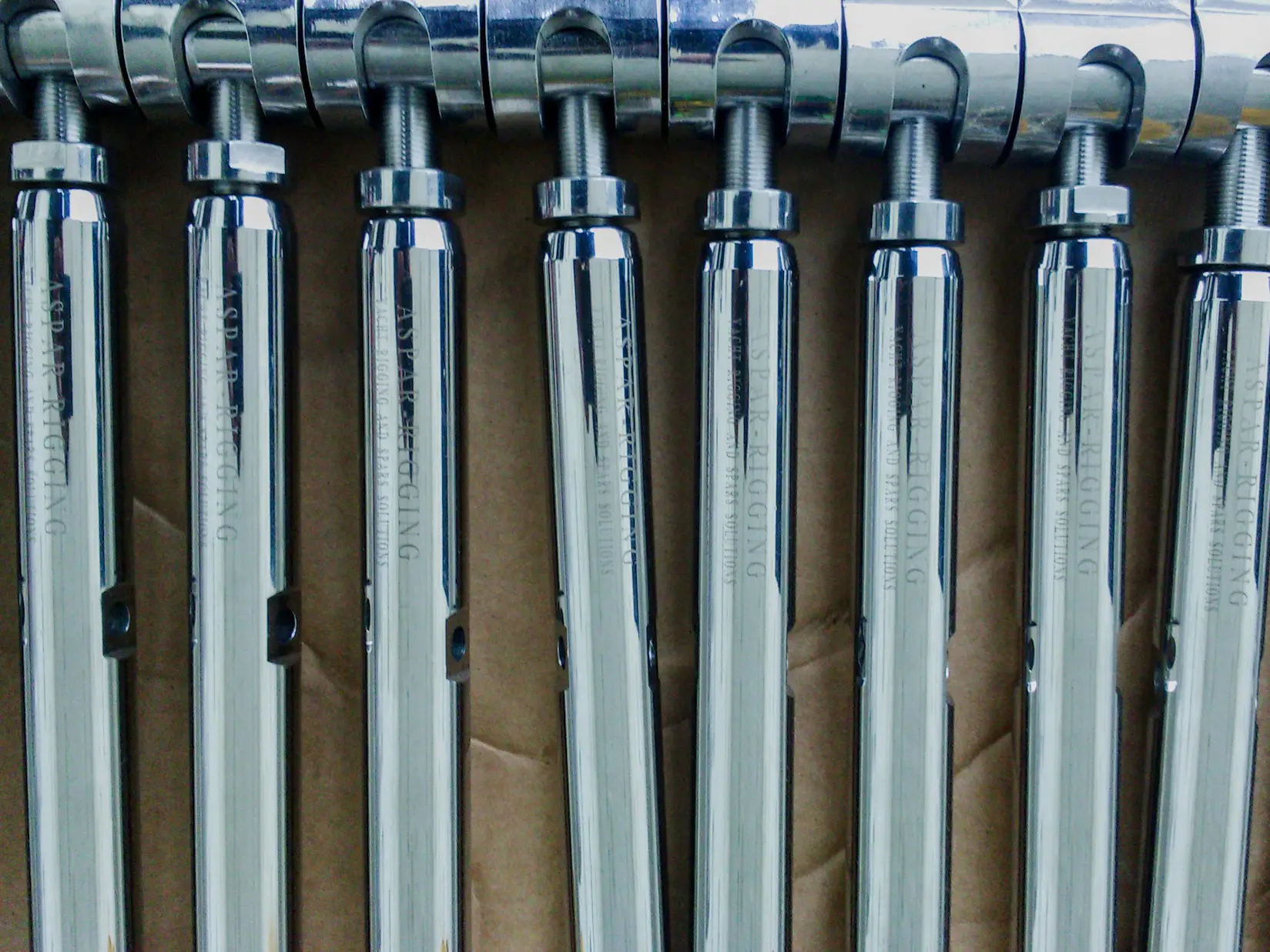 Custom rigging rods, fittings and metal components arranged on the ground in a boatyard